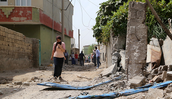 A woman walks along a street in the southeastern Turkish town of Silopi in Sirnak province, near the Turkish-Iraqi border crossing of Habur, Turkey, August 7, 2015. Five people were killed in eastern Turkey on Friday in a series of clashes between security forces and Kurdish militants, part of a surge in violence that has put further strain on a fragile peace process between Ankara and the rebels. Three people were killed and seven wounded during clashes between police and militants of the Kurdistan Workers Party (PKK) in the town of Silopi, authorities said. In two other separate incidents in Van and Agri provinces, the militants killed two soldiers, bringing the death toll among Turkish security forces since July 20 to at least 21. REUTERS/Sertac Kayar  - RTX1NHMZ